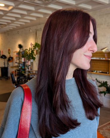 Client with long, sleek deep burgundy hair, in profile